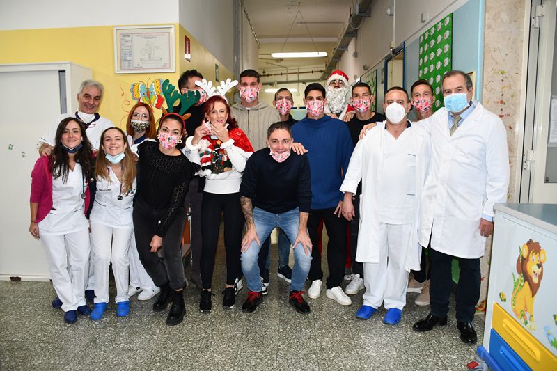 La Torres Calcio regala un sorriso ai bambini ricoverati in Pediatria Giocatori e dirigenti della storica società sportiva sassarese hanno portato in dono magliette e tanti gadget. Con loro anche Michela Sanna, la figlia dello storico calciatore e allenatore del sodalizio torresino e al quale è intitolato anche lo stadio comunale sassarese Sassari 15 dicembre 2023 - Hanno donato un momento di spensieratezza ai bambini presenti oggi nel Day hospital oncologico-pediatrico e a quelli ricoverati nel reparto della Clinica pediatrica. A farlo sono stati i giocatori della Sef Torres Calcio, Giuseppe Mastinu, Manuel Fischnaller, Nicolò Antonelli, Luigi Scotto e Riccardo Idda. Ed è stato proprio quest'ultimo, vestito da Babbo Natale, a portare i sacchi dei doni: magliette, braccialetti, borracce, quaderni, mascherine e cuscini da stadio, tutti rigorosamente con i colori e gli stemmi del sodalizio sportivo. La società, così, non ha dimenticato nessuno, regalando magliette con le giuste taglie, adatte ai più piccoli (tanti quelli di tre anni ricoverati) e ai più grandicelli (alcuni adolescenti). Ad accompagnare i giocatori erano presenti anche i dirigenti della società sportiva, Alessandro Gadau, Antonio Planetta e Paolo Scardaccio. I giocatori e i dirigenti della società sono stati accolti calorosamente dai piccoli pazienti e dal personale medico e infermieristico di turno nella clinica, al primo e secondo piano del Materno Infantile. "Un'iniziativa lodevole da parte di una grande e storica società di calcio che sta rappresentando in maniera egregia la città di Sassari e i sassaresi - ha detto il direttore del dipartimento Materno infantile dell'Aou di Sassari professor Giampiero Capobianco - e ci auguriamo che possa regalare alla comunità il sogno della B. Nel frattempo, i giocatori hanno regalato un sicuro momento di gioia e spensieratezza ai bambini ricoverati nella Clinica pediatrica, dove gli operatori sanitari, medici, infermieri e oss lavorano ogni giorno con altissima professionalità e tantissima umanità nei confronti dei bambini e dei loro genitori". A fare da Ciceroni nel reparto suddiviso tra due piani, sono stati il direttore della Clinica pediatrica Gianfranco Meloni e la coordinatrice Anna Maria Zara. "Ringraziamo la società sportiva Sef Torres Calcio per la graditissima visita - ha detto Gianfranco Meloni - per un gesto che avvicina due istituzioni storiche della città di Sassari, appunto la Torres e la nostra Clinica. Un ringraziamento va anche alla pediatra di base dottoressa Michela Sanna, figlia del grande Vanni Sanna, giocatore e allenatore della Torres e al quale è anche intitolato lo stadio comunale, che oggi ha accompagnato i calciatori in questa visita che ha donato ai nostri piccoli pazienti un momento di spensieratezza". Per la storica società di calcio la visita rappresenta una vera e propria tradizione, che viene ripetuta ogni anno. "Ci faceva piacere portare un sorriso a piccoli ricoverati - ha detto Alessandro Gadau, dirigente della Sef Torres Calcio - e donare così un pensierino attraverso i giocatori della squadra. Un appuntamento al quale la nostra società non voleva mancare, per essere vicini a coloro che operano per la comunità, per fare un augurio ai bimbi, alle famiglie e agli operatori che lavorano tanto, in silenzio e con grande impegno".